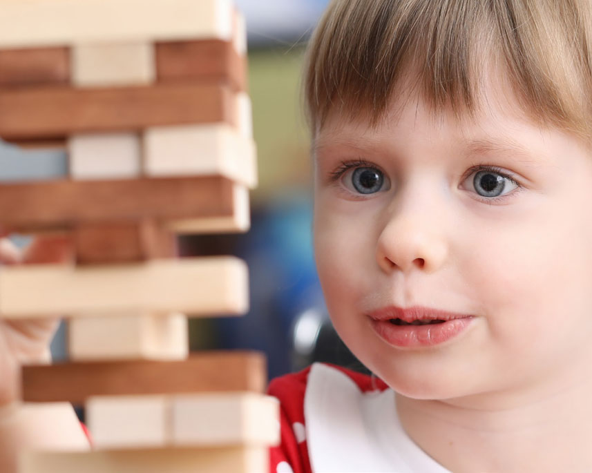child looks with wonder at wooden blocks